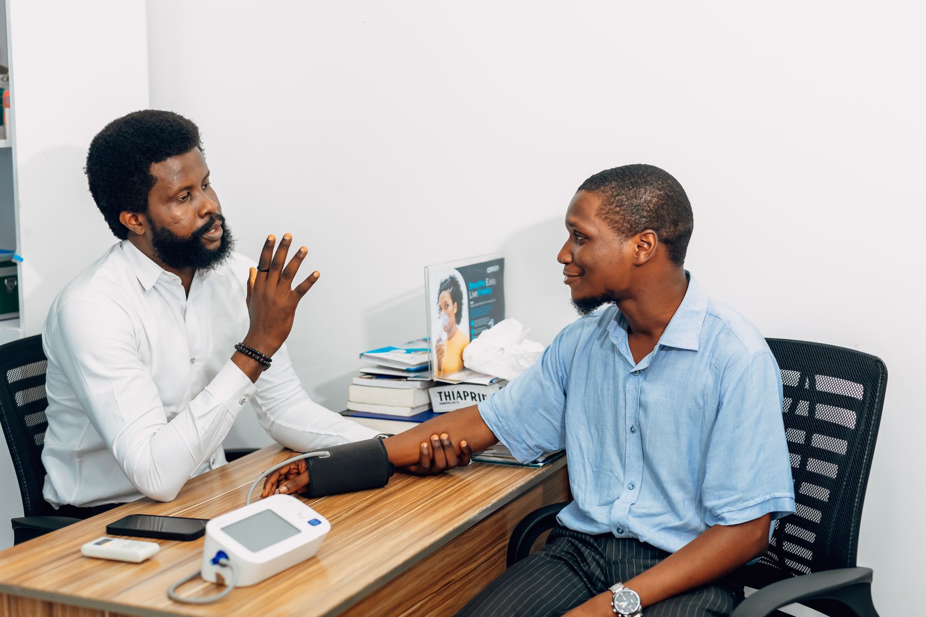 A clinician checking a patient’s blood pressure during a consultation in Lagos