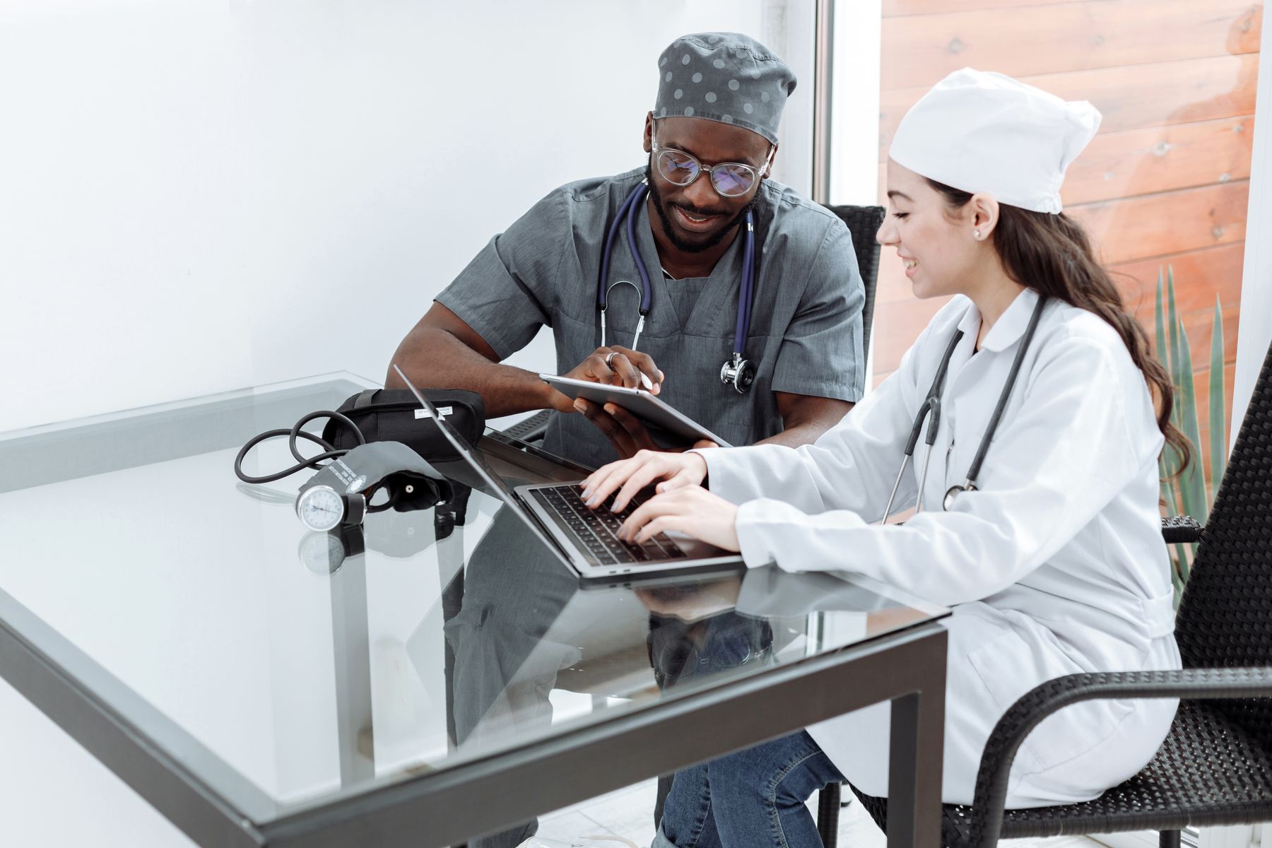 Two clinicians reviewing shared health information across a tablet and laptop